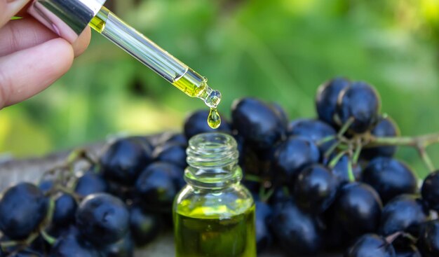 Olio di semi d'uva in un barattolo di vetro e uva fresca per spa e cura del corpo Il concetto di prodotti ecologici spa