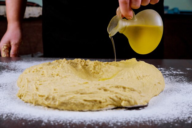 Olio di versamento della donna sulla pasta di lievito per produrre pane