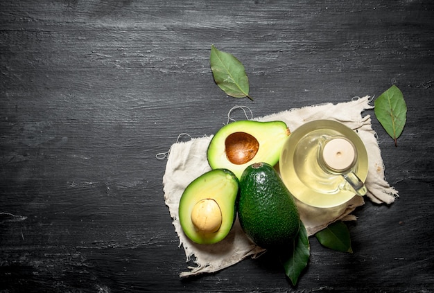 Olio e avocado. Su uno sfondo di legno nero.