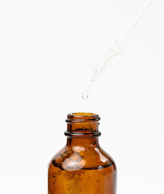 Olio essenziale che cade dal contagocce di vetro ambrato Bottiglia blu di olio cosmetico con una pipetta