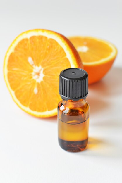 Olio essenziale di agrumi arancio in bottiglia di vetro scuro con frutta fresca di arancia