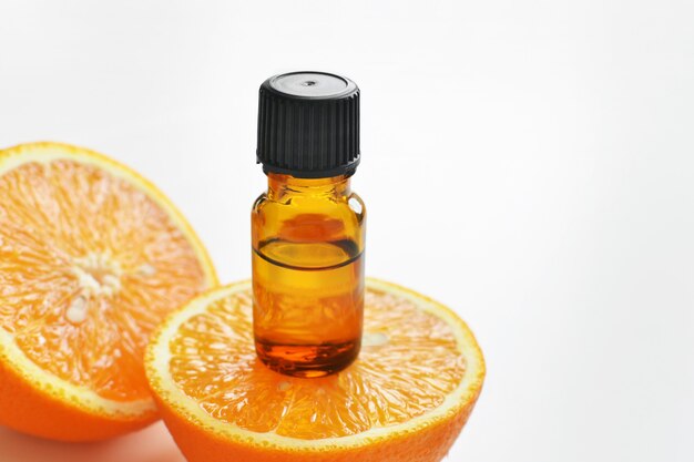 Olio essenziale di agrumi arancio in bottiglia di vetro scuro con frutta fresca di arancia