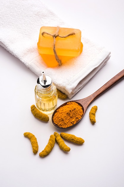 Olio essenziale di curcuma con sapone e bastoncini Haldi secchi e polvere in un cucchiaio di legno