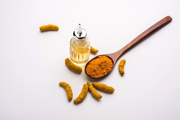 Olio essenziale di curcuma con sapone e bastoncini Haldi secchi e polvere in un cucchiaio di legno