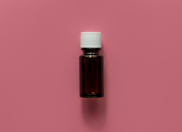 Olio essenziale di erbe bottiglia di vetro mockup sfondo rosa pastello Medicina alternativa cura della pelle spa aromaterapia