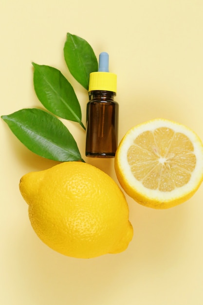 Olio essenziale di limone Estratto di limone in una bottiglia marrone, limone e foglie di limone