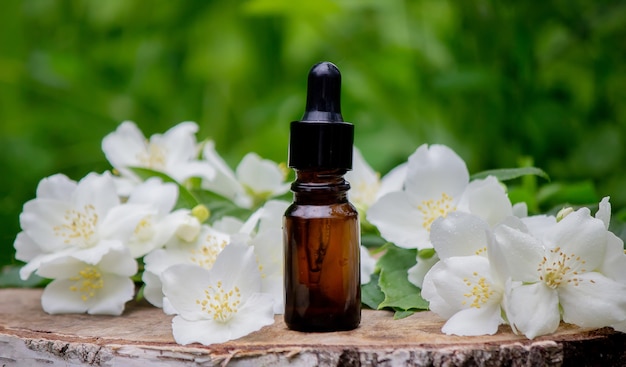 Olio essenziale e fiori di gelsomino su fondo in legno. Procedure cosmetiche. Messa a fuoco selettiva