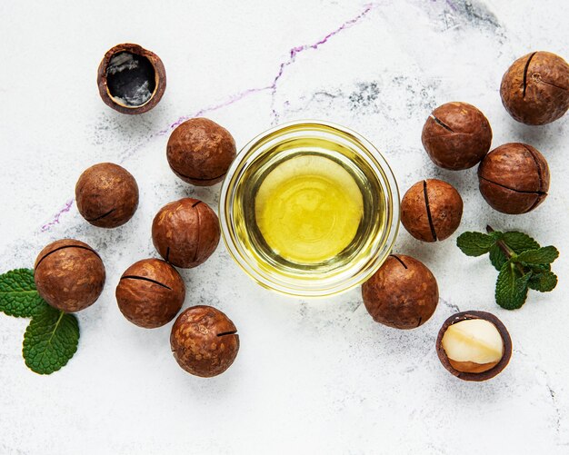 Olio naturale di macadamia e noci di macadamia sul tavolo di marmo