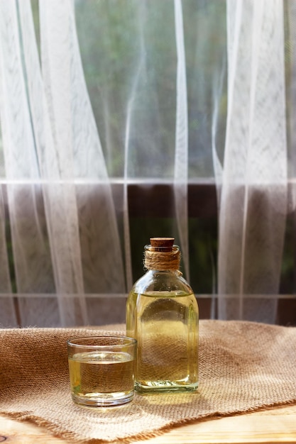 Olio vegetale in una bottiglia di vetro sullo sfondo del tessuto di tela di juta