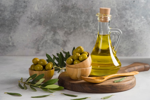 Olive e olio d'oliva su tavola di legno con fondo grigio ciotola