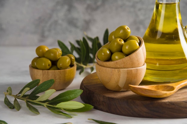 Olive e olio d'oliva su tavola di legno con fondo grigio ciotola