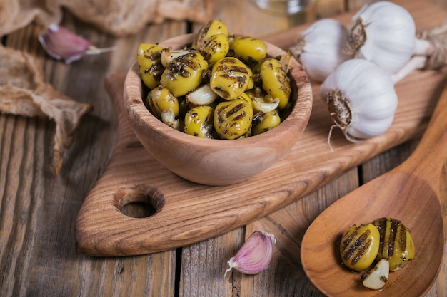 Olive grigliate con aglio olio d'oliva e spezie su fondo di legno