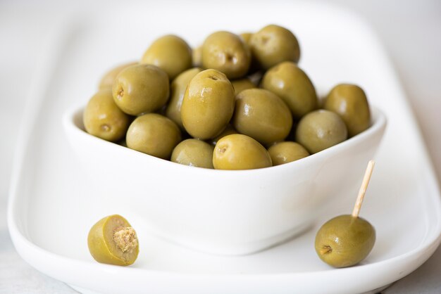 Olive in scatola con noccioli in una ciotola bianca