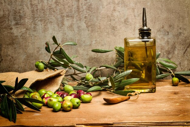 Olive in un sacco di tela e una bottiglia di vetro di olio d'oliva su un tavolo di legno