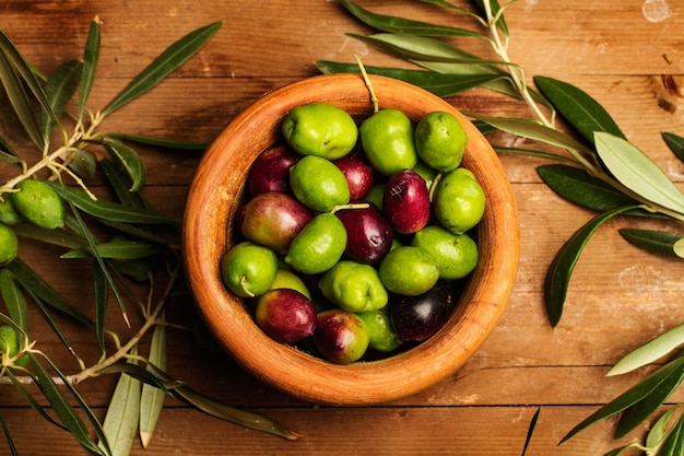 Olive in una ciotola di legno e su un tavolo di legno in una vista dall'alto