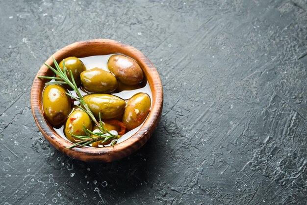 Olive marinate in una ciotola di legno su fondo di pietra Spazio libero per il testo