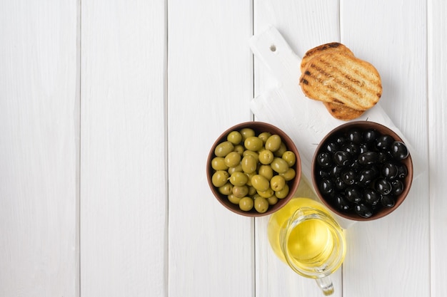 Olive nere e verdi su fondo di legno bianco