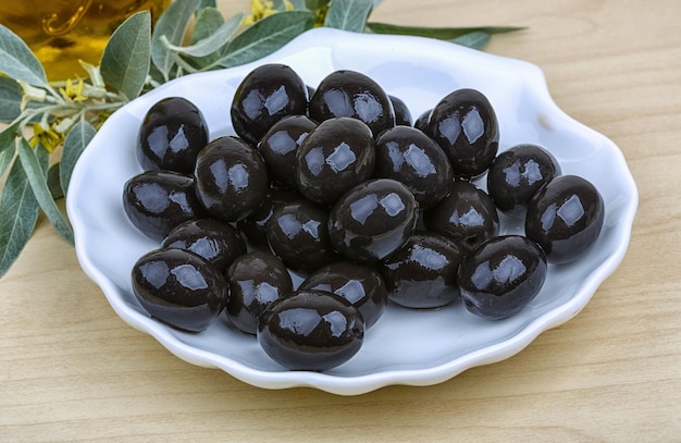 Olive nere nella ciotola con olio e foglie