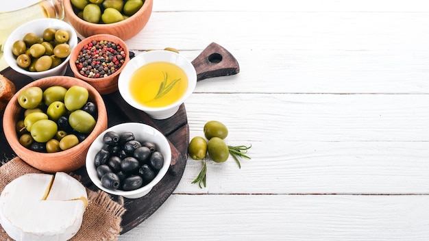 Olive verdi e olive nere pane all'olio formaggi e snack Cucina italiana Su un tavolo di legno bianco Vista dall'alto Spazio libero per il testo