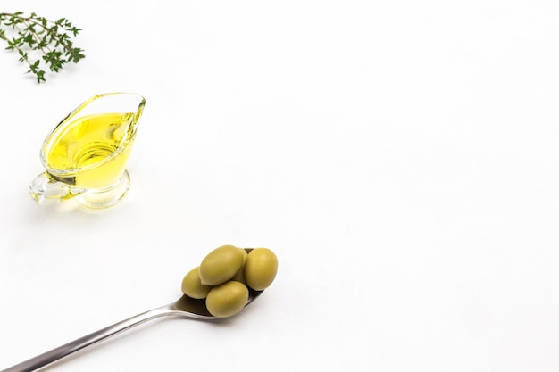 Olive verdi in cucchiaio di metallo Olio d'oliva in barattolo di vetro Raggi di timo