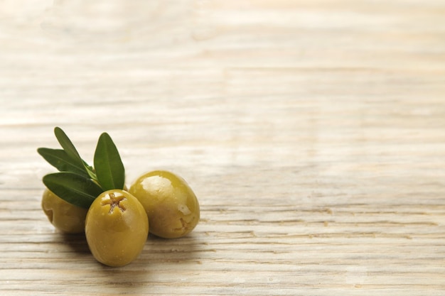 Olive verdi in una ciotola con foglie su un tavolo di legno naturale. avvicinamento. posto per il testo.