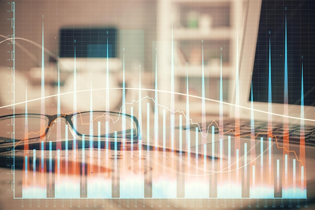 Ologramma grafico finanziario con gli occhiali sullo sfondo del tavolo Concetto di business Doppia esposizione