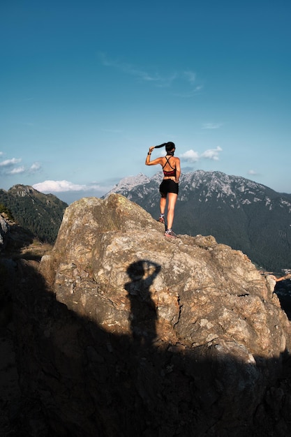 Ombra di un fotografo che ritrae una sportiva su una roccia