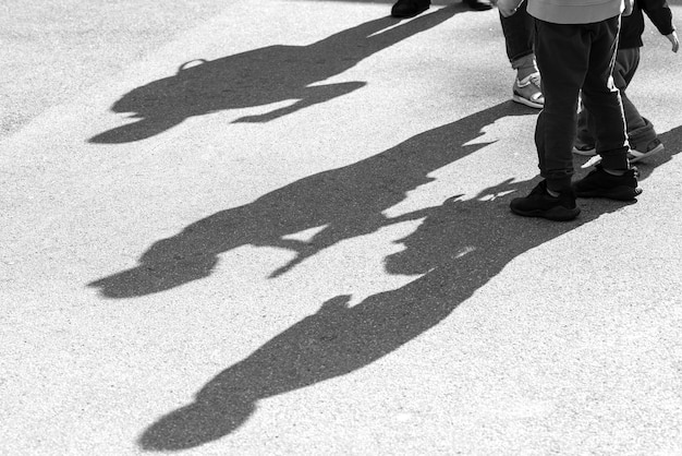 Ombre e sagome di tre bambini che giocano in una strada sulla superficie della strada asfaltata