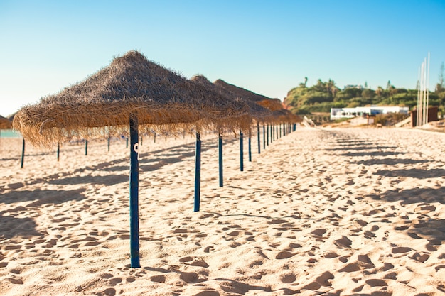 Ombrelli di paglia alla spiaggia tropicale vuota sulla costa atlantica