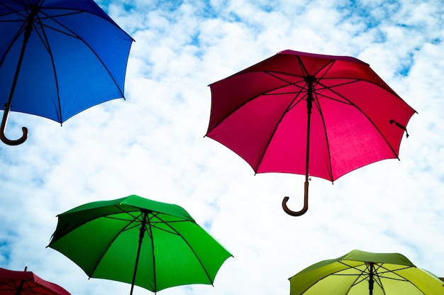 Ombrelli multicolori con sfondo azzurro del cielo Decorazione colorata della via dell'ombrello