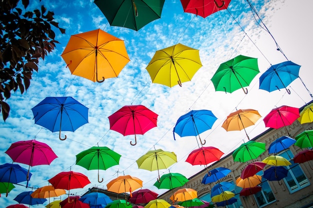 Ombrelli multicolori con sfondo azzurro del cielo Decorazione colorata della via dell'ombrello