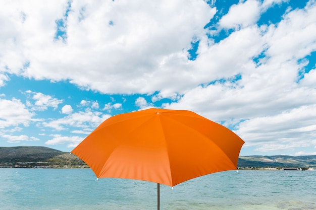 Ombrello arancione sul collage sulla spiaggia