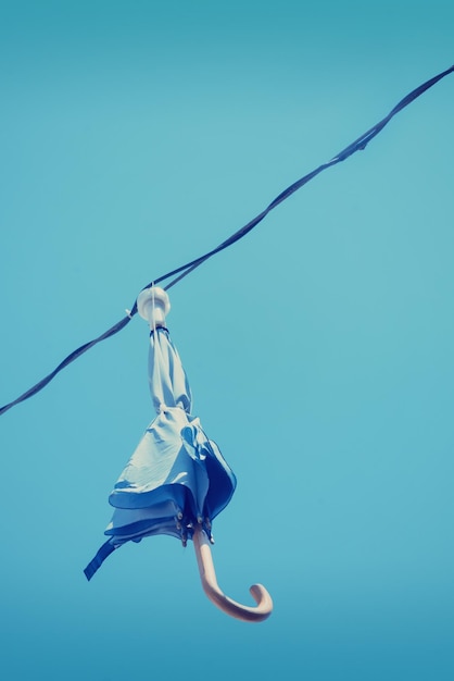 Ombrello chiuso con lampada appesa a un filo contro il cielo blu