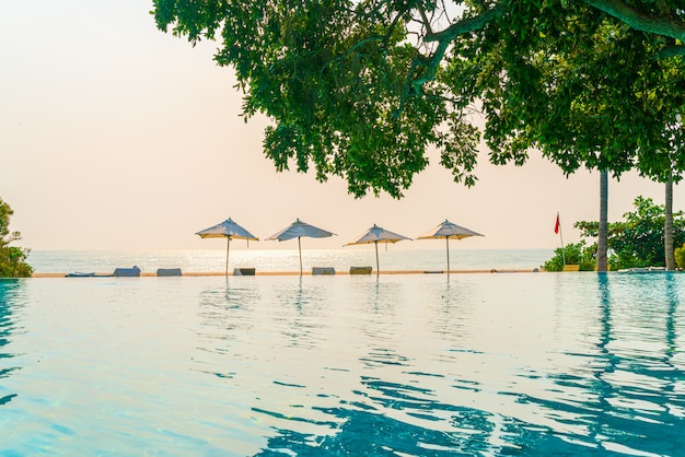 Ombrello e sedia intorno alla piscina con la vista sull'oceano del mare per il concetto di viaggio di vacanza di festa