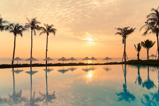 ombrellone con lettino piscina intorno alla piscina con sfondo del mare oceano al tramonto o all'alba - concetto di vacanza e vacanza