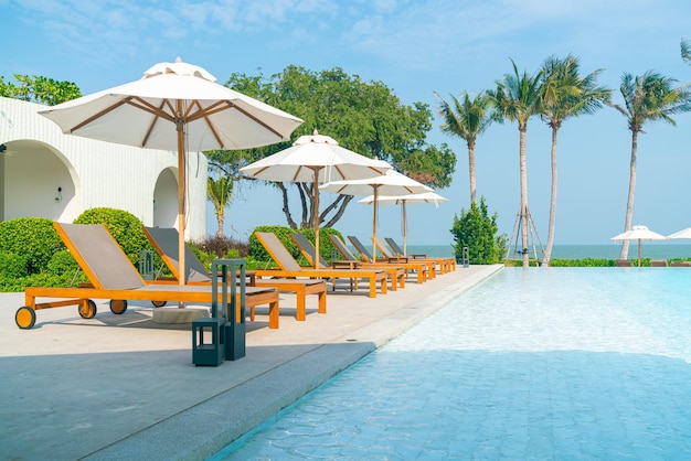ombrellone con piscina intorno alla piscina con sfondo oceano mare - concetto di vacanza e vacanza