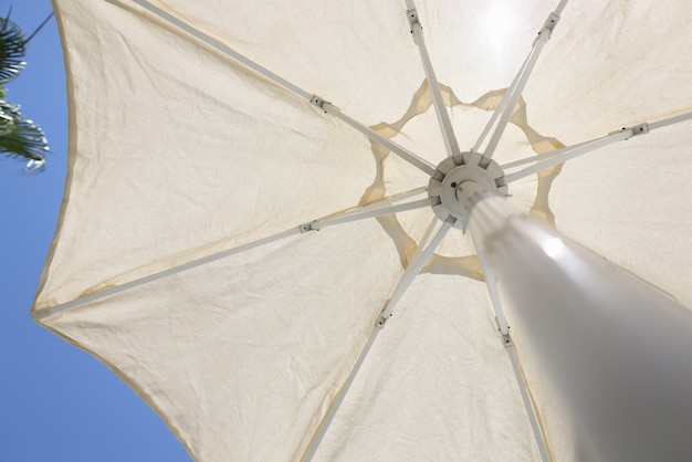 Ombrellone da spiaggia bianco contro il primo piano di vista dal basso del cielo blu