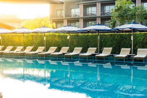 Ombrellone e lettino a bordo piscina intorno alla piscina all'aperto nel resort dell'hotel per vacanze di viaggio