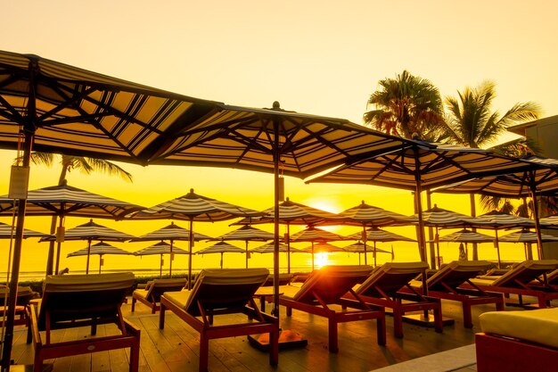 Ombrellone e poltrona divano intorno alla piscina all'aperto nel resort dell'hotel per vacanze di viaggio con cielo al tramonto o all'alba