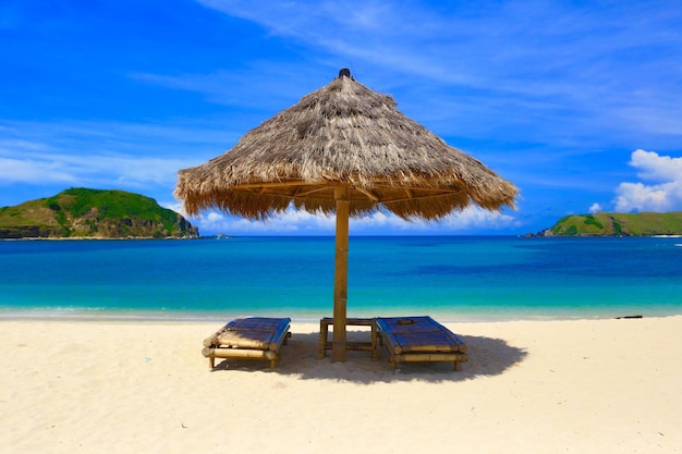 Ombrellone e sedie di paglia sulla spiaggia di Tanjung Aan, Mandalika, isola di Lombok, Indonesia