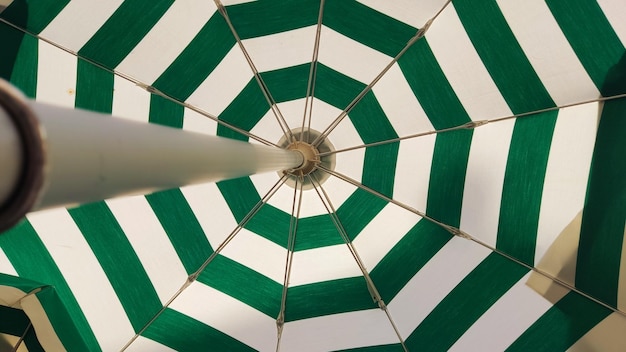 Ombrellone per bar all'aperto con strisce verdi e bianche. Un ombrello aperto che protegge dal sole, un umb