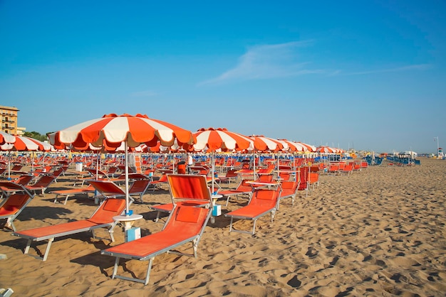 Ombrelloni arancioni e chaise longue sulla spiaggia di Rimini in Italia la destinazione della costa adriatica dell'EmiliaRomagna