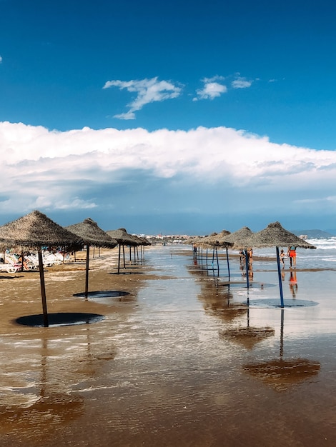 Ombrelloni di paglia sulla spiaggia bagnata