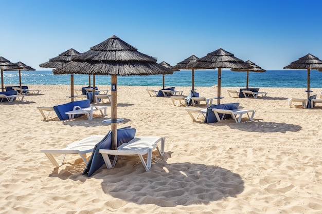 Ombrelloni e lettini sulla spiaggia meridionale dell'Algarve. Portogallo.