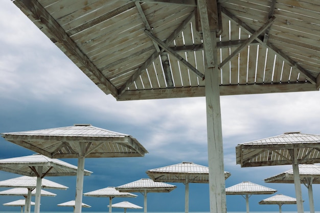 Ombrelloni in legno e sedie a sdraio vuote sulla spiaggia deserta in una giornata nuvolosa fuori stagione