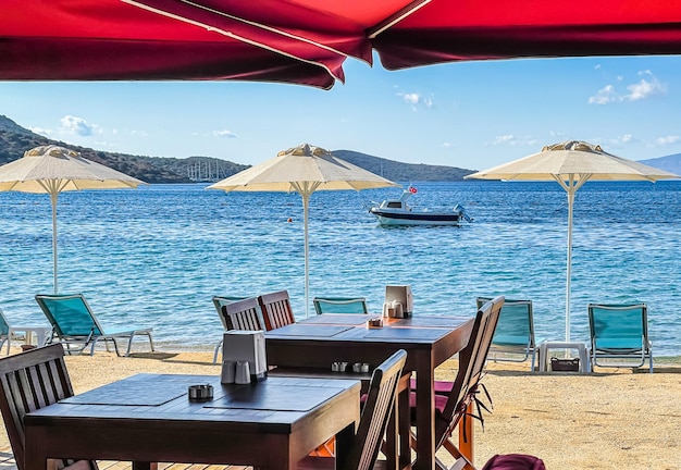 Ombrelloni lettini lettini tavoli e sedie sulla riva della baia blu del mare Concetto di vacanza estiva