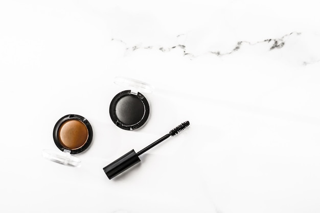 Ombretti fodera nera e mascara su sfondo marmo ombretti cosmetici come prodotti per il trucco glamour per il design flatlay di lusso del marchio di bellezza per le vacanze