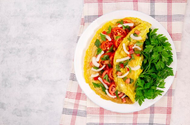 Omelette con prezzemolo e pomodori in una padella su uno sfondo grigio vista dall'alto