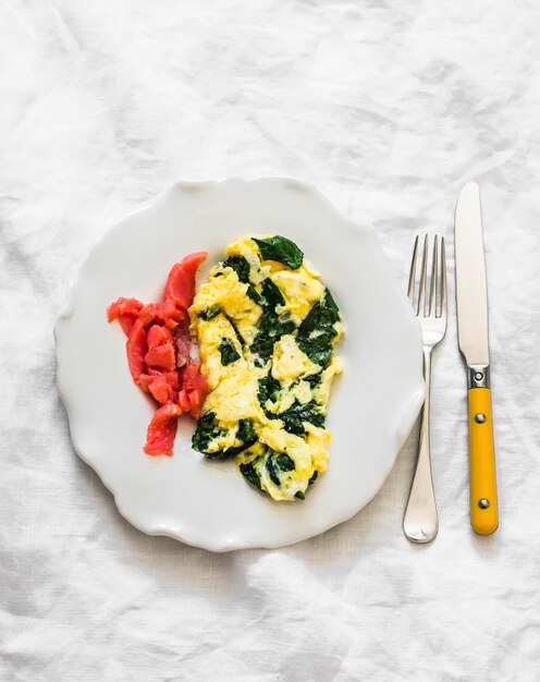 Omelette di spinaci e salmone leggermente salato delizioso brunch a colazione su uno sfondo chiaro vista dall'alto