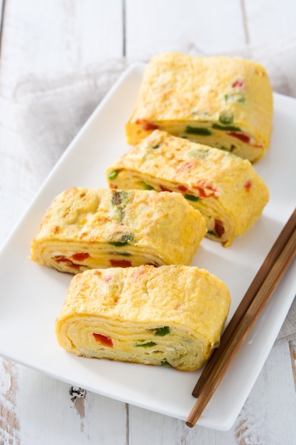 Omelette giapponese tradizionale di tamagoyaki sulla tavola di legno bianca.